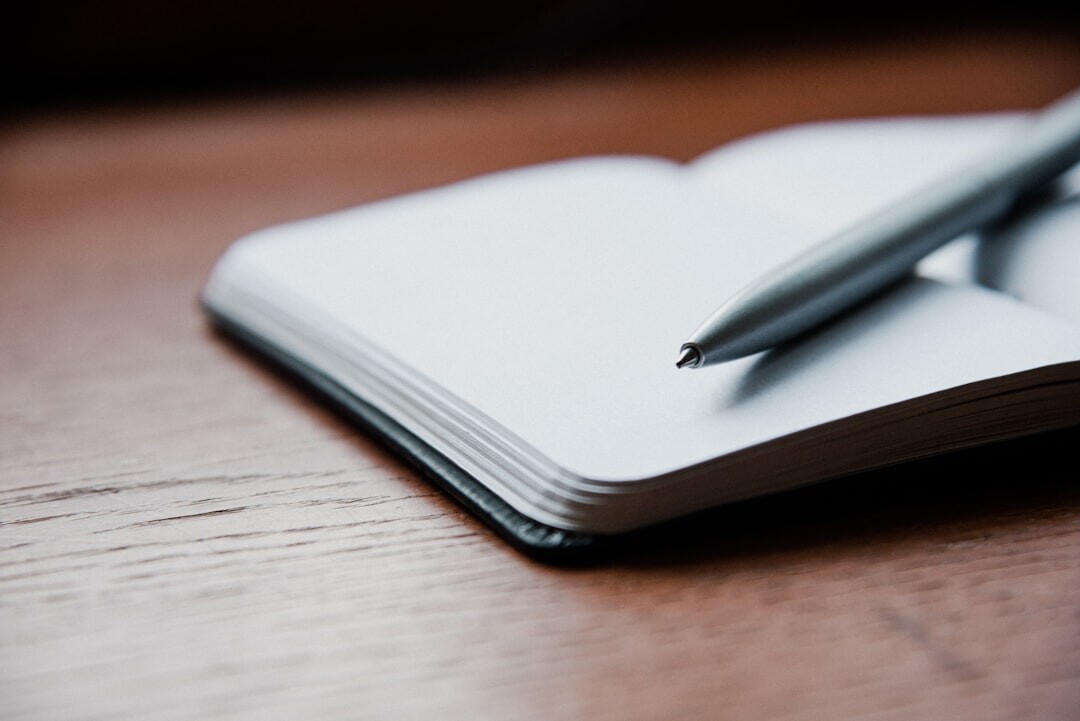 Open notebook with pen and coffee cup on a wooden desk